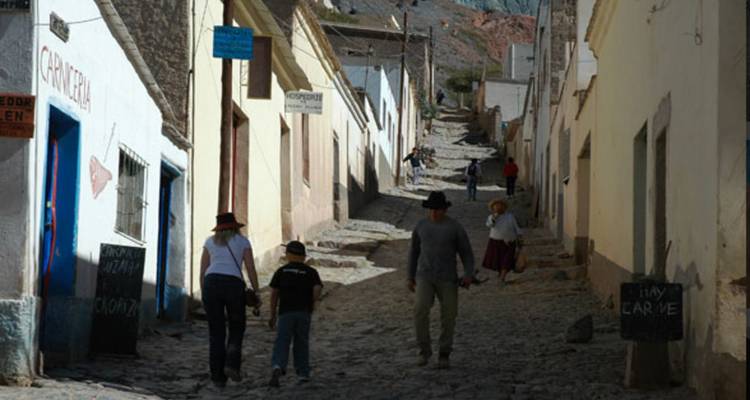 Een smalle straat met mensen die bergopwaarts lopen tussen oude stenen gebouwen.