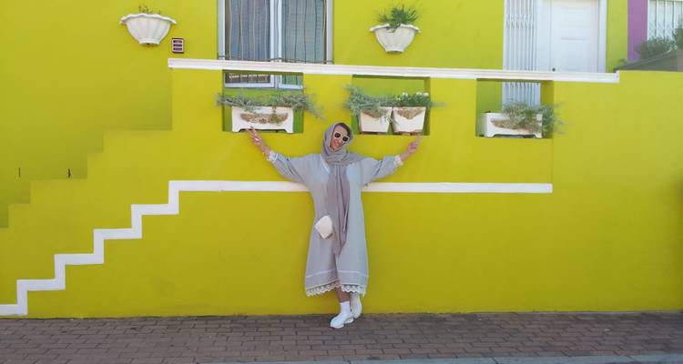 A person posing in front of a colorful building.