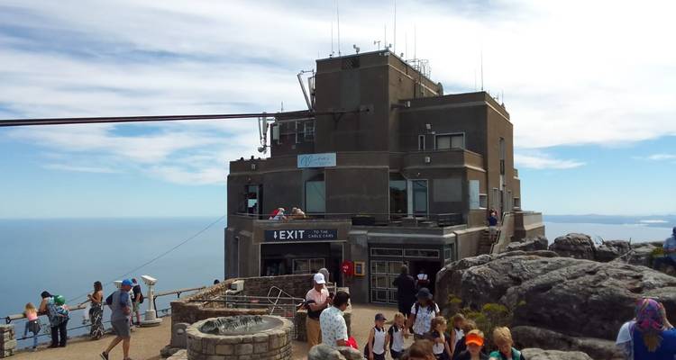 A cable car station at the top of a mountain with ocean in the background.