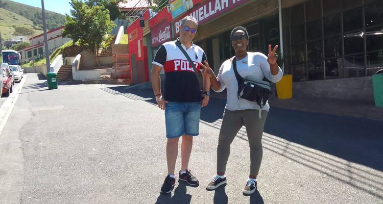 Two people posing on a street with buildings in the background.