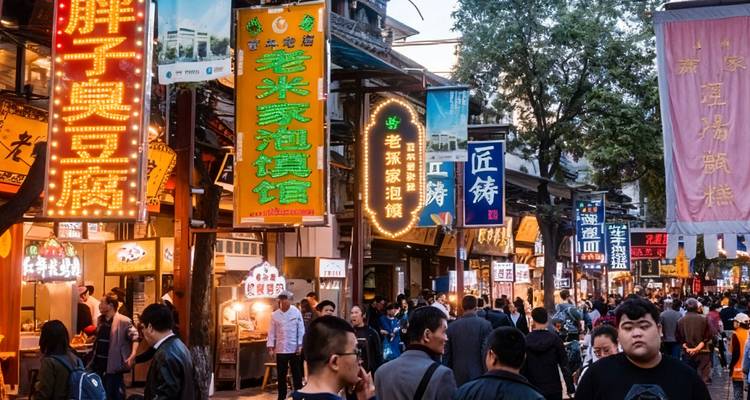 Crowded street with colorful signs and shops, people walking around.