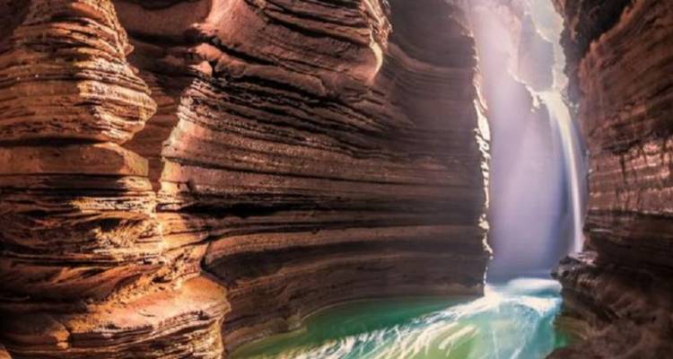 Canyon with a waterfall flowing into turquoise waters.