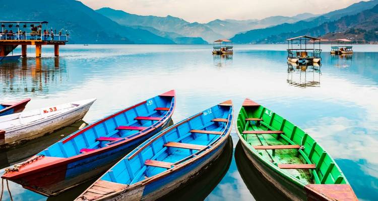 Colorful boats on a serene lake with mountains in the background.