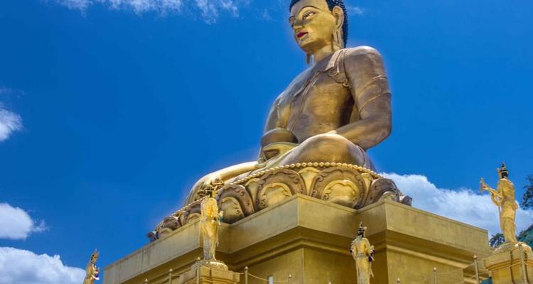 Large golden statue of Buddha under a clear blue sky.