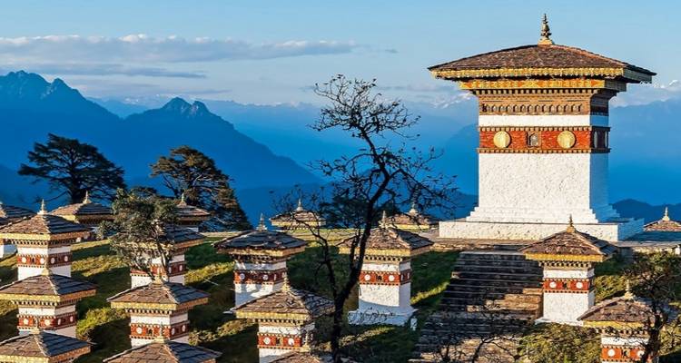Unique structure with numerous small stupas against a mountain backdrop.