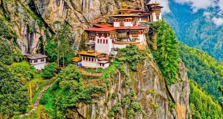Monastery hanging on a cliffside surrounded by forest.
