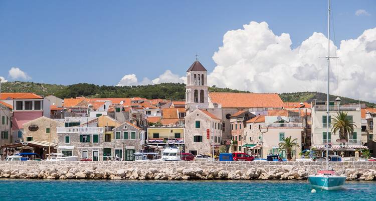 A coastal village with colorful buildings and a sailboat in the foreground.