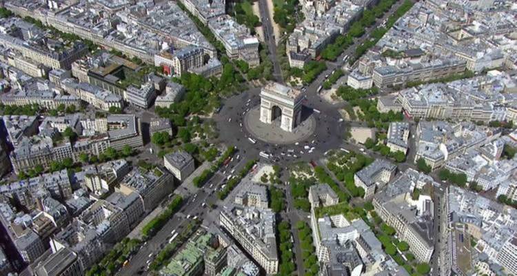Aerial view of Arc de Triomphe surrounded by streets and buildings.