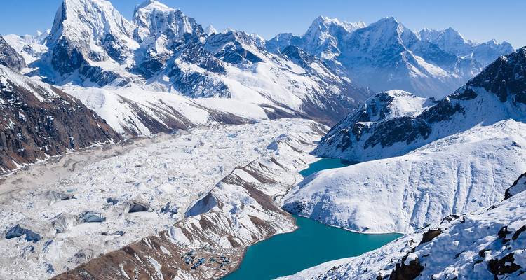 Paisaje montañoso sereno con lago turquesa y glaciares.