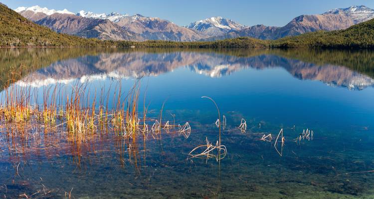 Snow-capped mountains reflected in a calm lake.