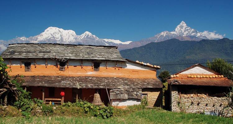 Traditional Nepali house with mountains in the background.