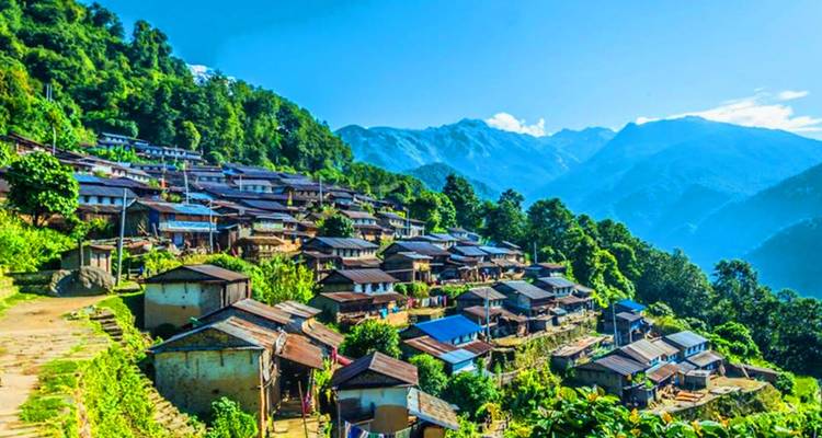 A village nestled in a verdant mountain landscape under a clear sky.