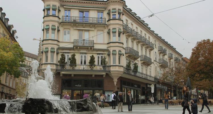 Zone piétonne avec boutiques et cafés dans une ville européenne.