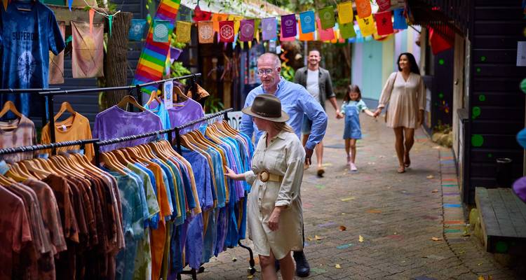 Kleurrijke marktstraat met batik kledingstalls en bezoekers die rondkijken onder feestelijke vlaggen