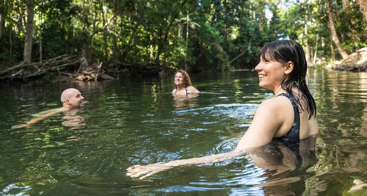 Vrienden die zwemmen en ontspannen in een heldere regenwoudrivier omgeven door dichte begroeiing