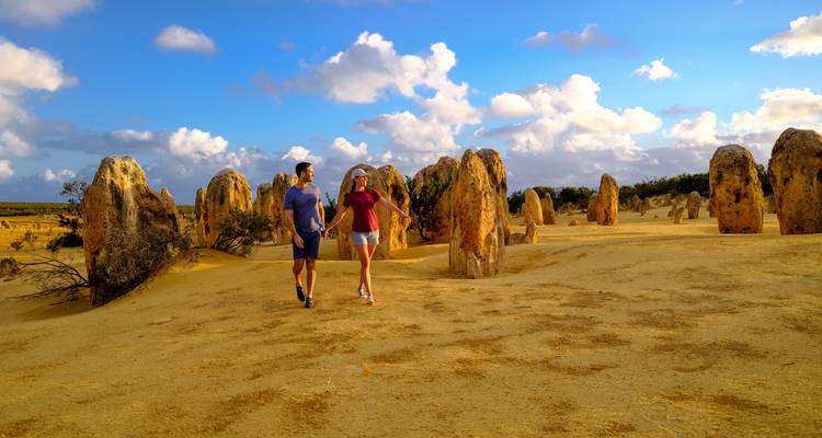 Couple strolls hand-in-hand among the weathered limestone spires of the Pinnacles Desert.