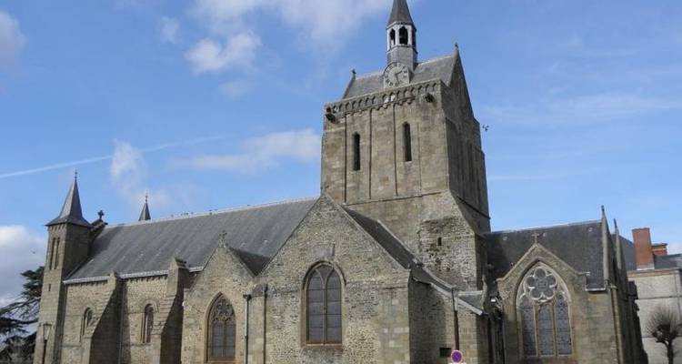 Stone church with a tall bell tower under a blue sky.