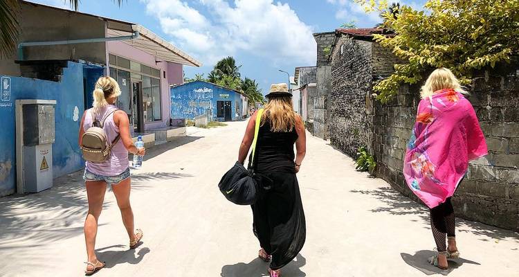 Trois femmes marchant dans une rue sablonneuse d'une ville balnéaire.