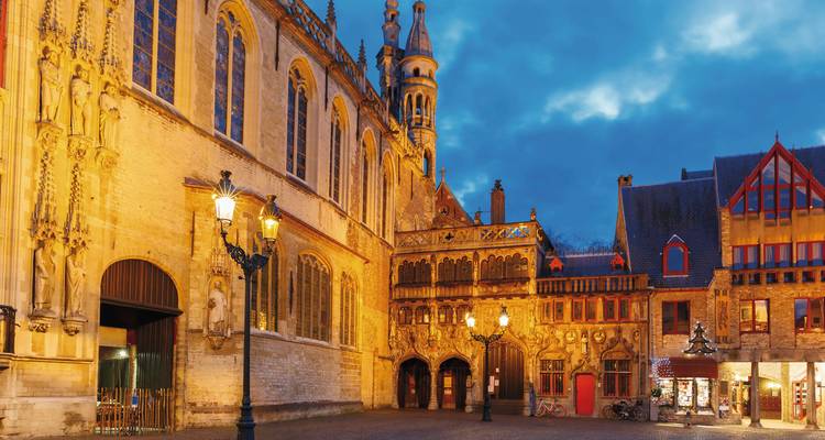 Historic building in a cobblestone square with evening lighting.
