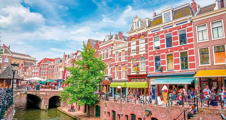 Scène animée de canal avec des gens qui dînent à l'extérieur de bâtiments historiques.