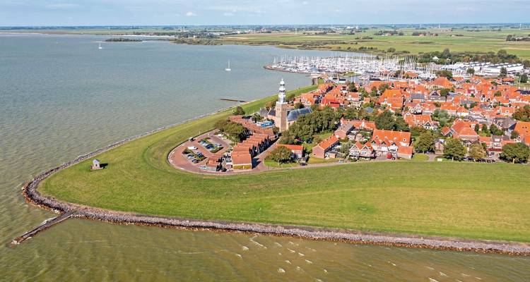 Vue aérienne d'une ville côtière avec un phare et un port de plaisance.