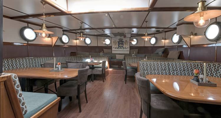 Innenraum eines Schiffes mit Holztischen und -stühlen