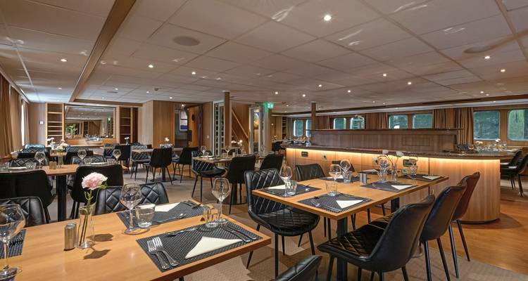 Elegantes Esszimmer mit mehreren Tischen und Stühlen eingerichtet.