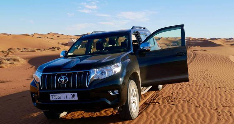 Four-wheel drive vehicle parked on sand dunes in the desert.