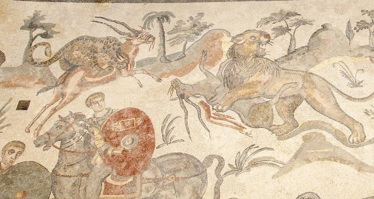 Detallado mosaico romano antiguo que muestra cazadores, animales y escenas mitológicas en el piso de una villa.