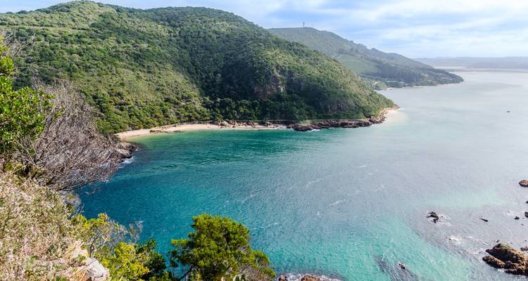 Luchtfoto van een kustbaai met helder water en kliffen.