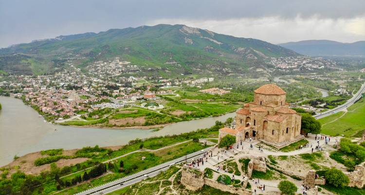 Klooster op een heuvel met uitzicht over een rivier en stad.
