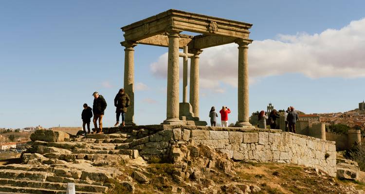 Anciens piliers de pierre avec des personnes explorant le site.