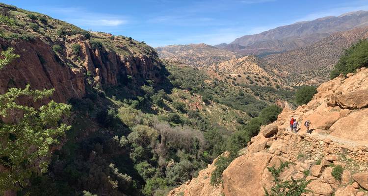 Hikers exploring a scenic canyon with mountains in the background.