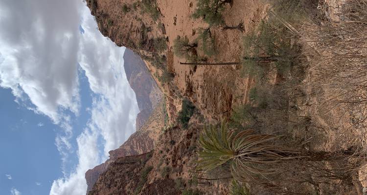 Scenic mountainous landscape with clouds and sparse vegetation.
