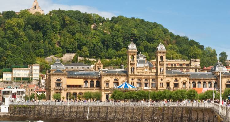 Seaside view of Ayuntamiento de San Sebastian with tourists walking in front.