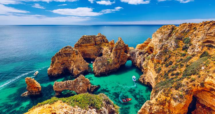 Falaises spectaculaires avec une eau turquoise et des bateaux dans une crique.