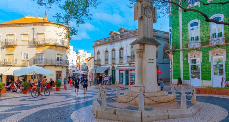 Place européenne animée avec des bâtiments historiques et des cafés en terrasse.