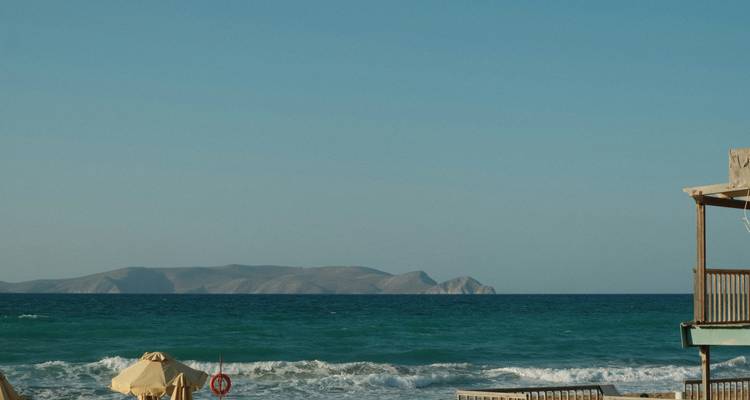 Beach scene with waves and distant mountains.