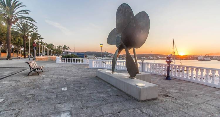 Eine Skulptur und Promenade bei Sonnenuntergang in der Nähe eines Hafens.