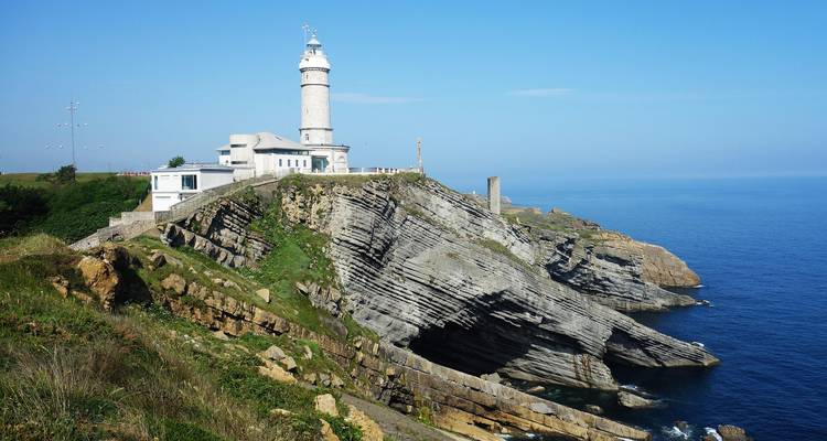 Phare au sommet d'une falaise rocheuse avec l'océan en arrière-plan.