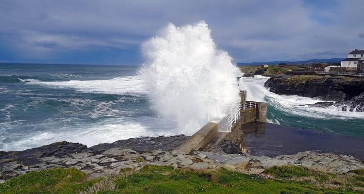 Vagues océaniques s'écrasant contre une structure côtière rocheuse.