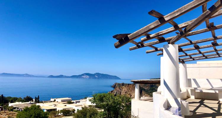 Eine Terrasse mit Blick auf das blaue Meer und entfernte Inseln.