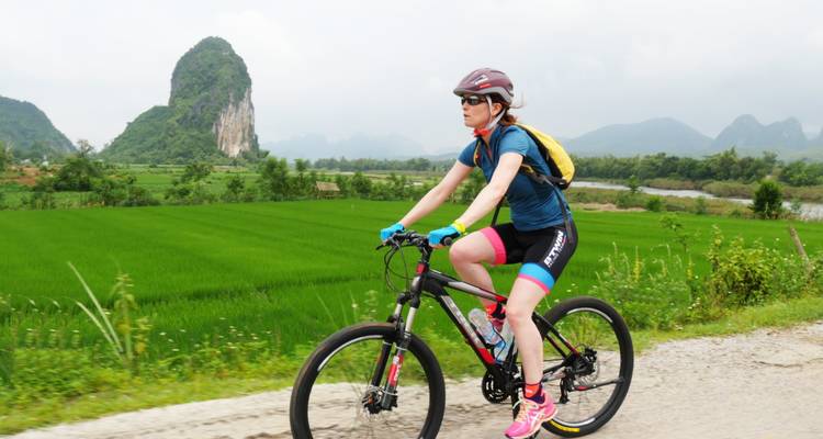 Cyclist riding through scenic countryside with limestone hills.