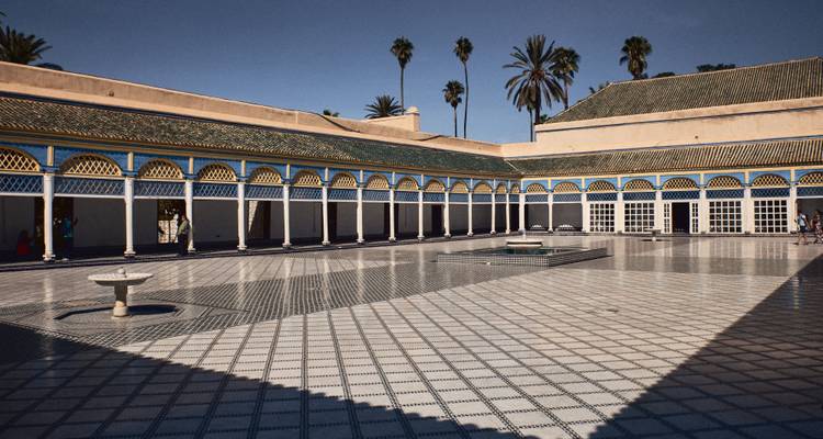 Cour élégante au carrelage du Palais de la Bahia avec des arcs marocains et des bordures bleues.