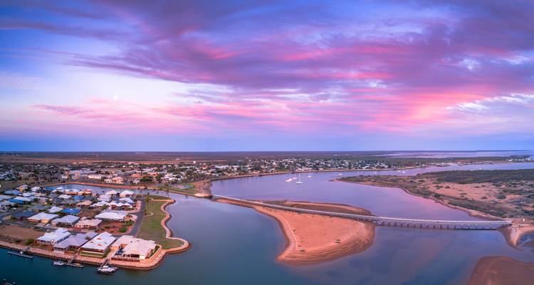 Aerial view of a coastal town with pink clouds in the sky.
