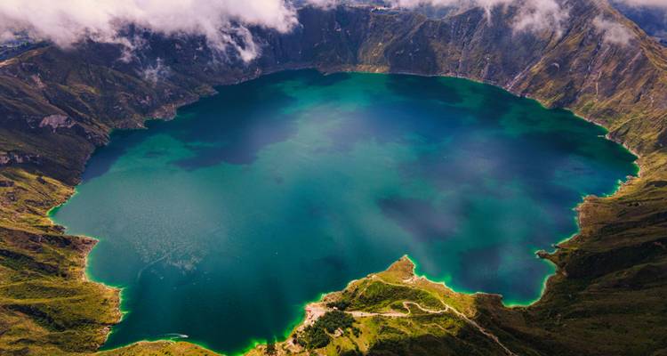 Aerial view of a pristine blue crater lake surrounded by mountains.