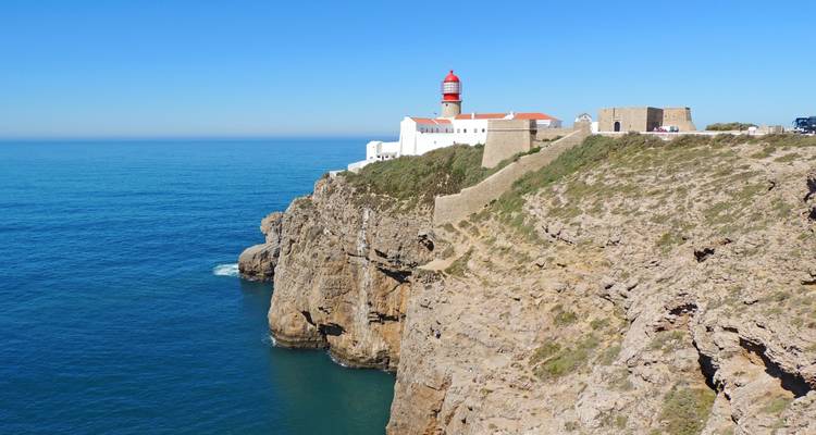 Icónico faro de techo rojo y fortaleza posados dramáticamente sobre altos acantilados sobre el profundo océano Atlántico azul.