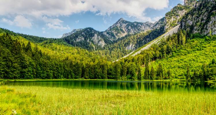 Serene mountain lake with surrounding peaks and forest.