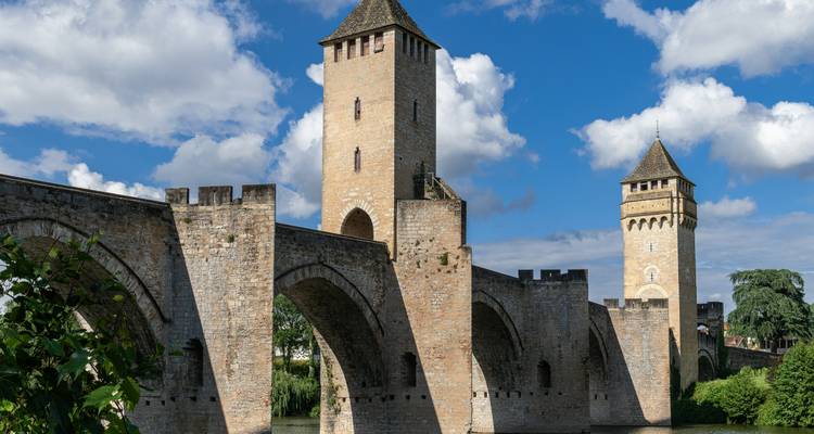 Mittelalterliche Steinbrücke mit Türmen unter bewölktem Himmel.