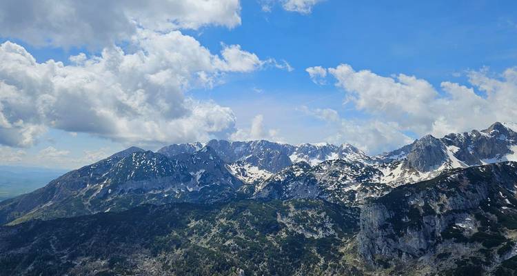 Dramatic view of rugged mountains with snow caps and a vibrant sky.